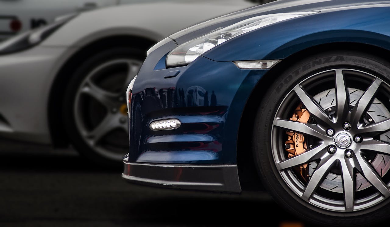 Detailed view of high-performance luxury cars showcasing wheels and design at a race event.